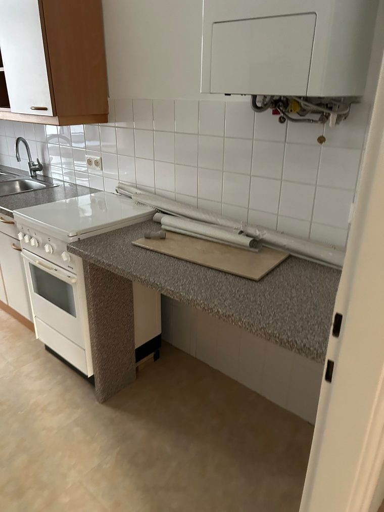 Küche einer Wohnung vor der Endreinigung, auf der Arbeitsplatte liegen noch Reste