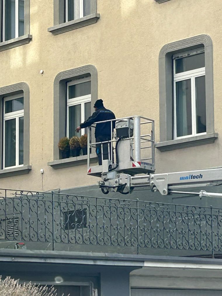 Reinigungskraft in der Arbeitsbühne eines Hubsteigers an einer Altbaufassade