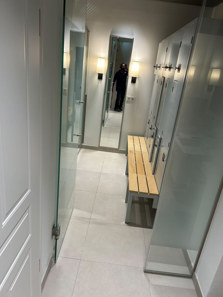 Garderobe eines Fitnessstudios mit Spinden, Sitzbank und Fliesenboden nach der Reinigung