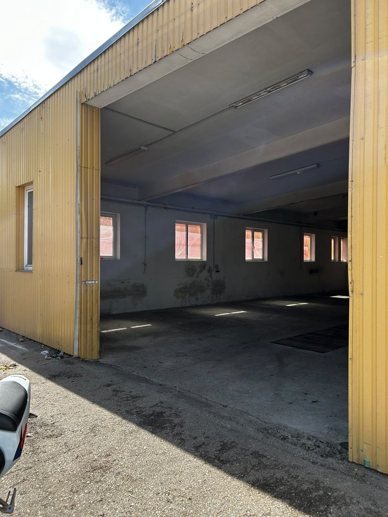 Geöffnetes Schiebetor einer Werkhalle mit Blick in die leere Halle