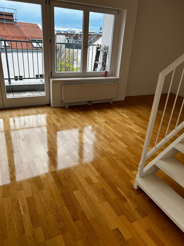 Eichenparkett in einem Wohnraum mit Balkontür und weißer Treppe