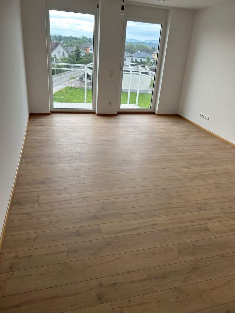 Leerer Raum mit Bodenbelag in Holzoptik und Terrassentür