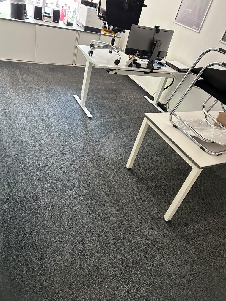 Dunkelgrauer Büroteppichboden mit gleichmäßigem Flor und Arbeitsplätzen