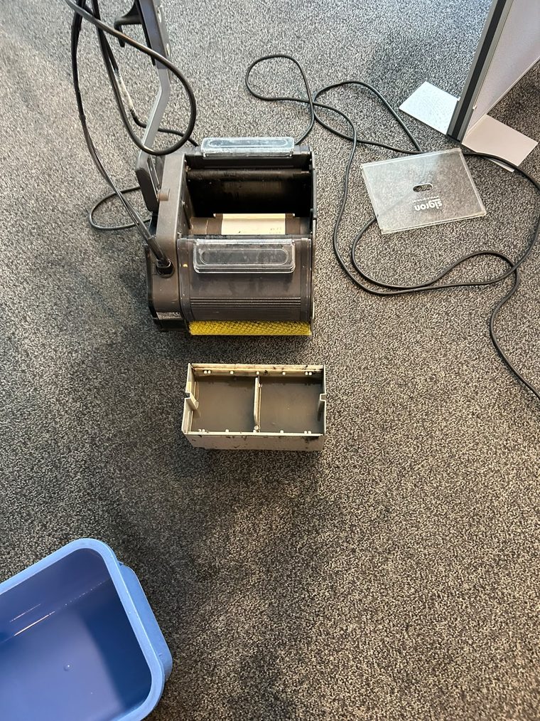 Bürstenmaschine mit Bürstenwalze und Schmutzwasserwanne auf einem Büroteppichboden