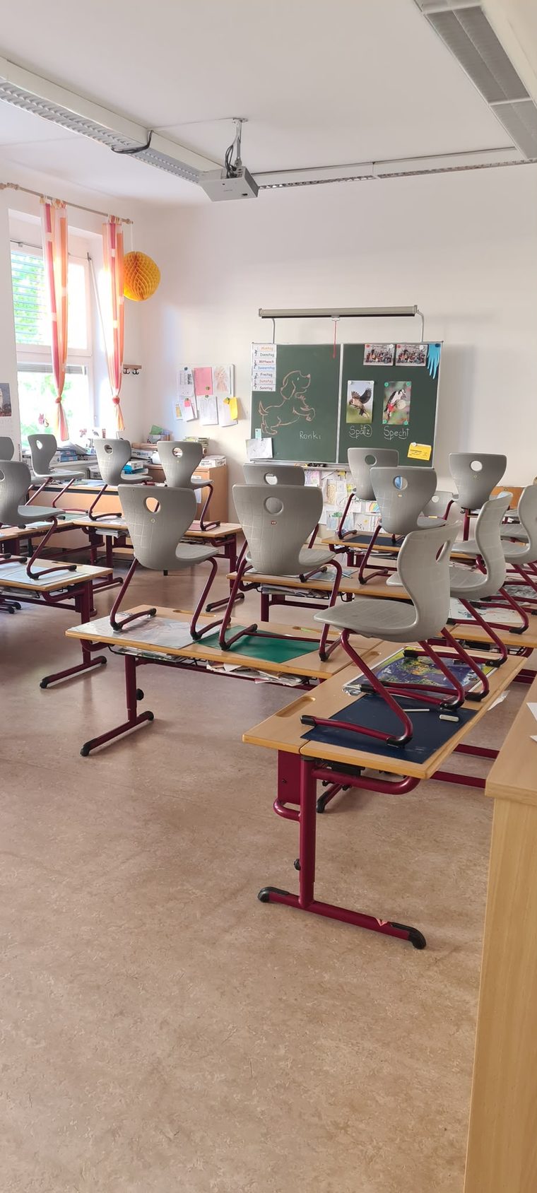 Klassenzimmer einer Schule mit hochgestellten Sesseln auf den Tischen und grüner Tafel