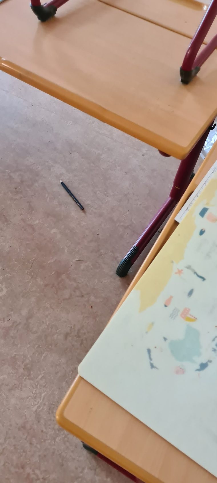 Schultisch im Klassenzimmer aus der Nähe, daneben der Boden zwischen den Reihen
